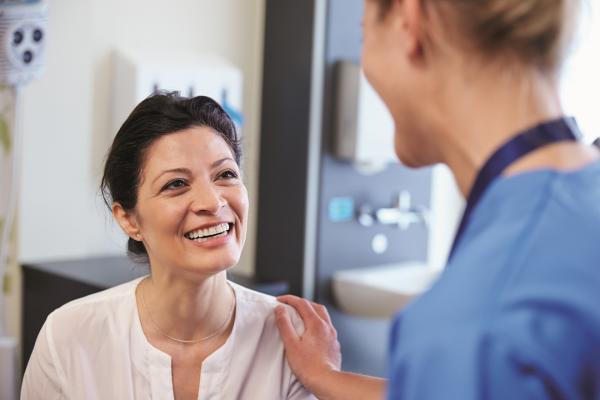 Lächelnde Patientin im Gespräch mit Ärztin 
